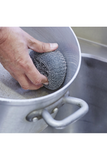 Hand using stainless steel scourer on metal pan.